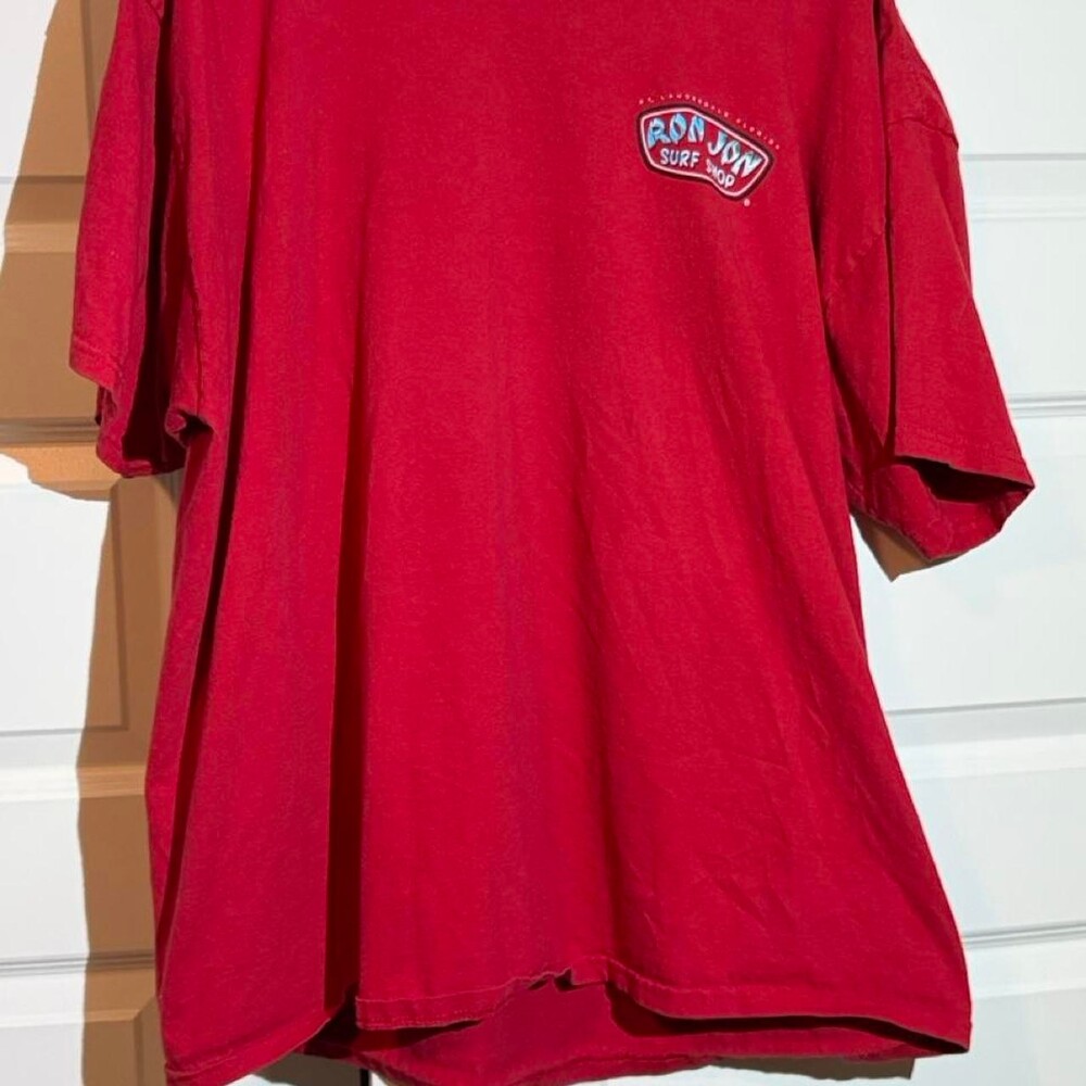 Red Ron Jon Surf Shop T-shirt with blue graphic of a surfboard with the words 'R